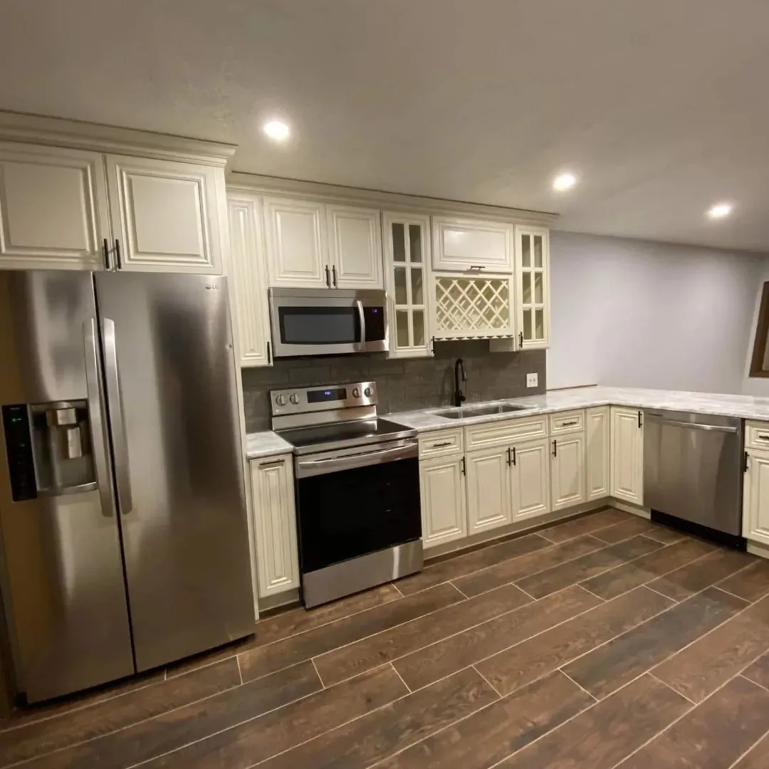 Renovated kitchen with cream shaker cabinets, stainless steel appliances, a built-in wine rack and wood-look tile flooring.